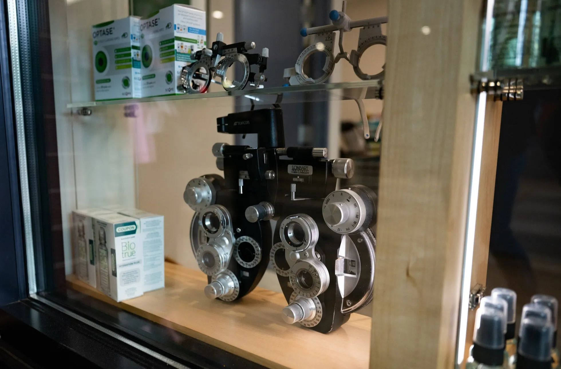 A phoropter and trial frames in a window display case at Voorthuis Opticians.