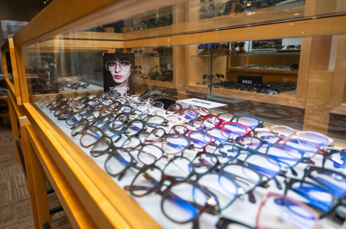 A glass display case of designer eyeglass frames with a Tom Ford lookbook card at Voorthuis