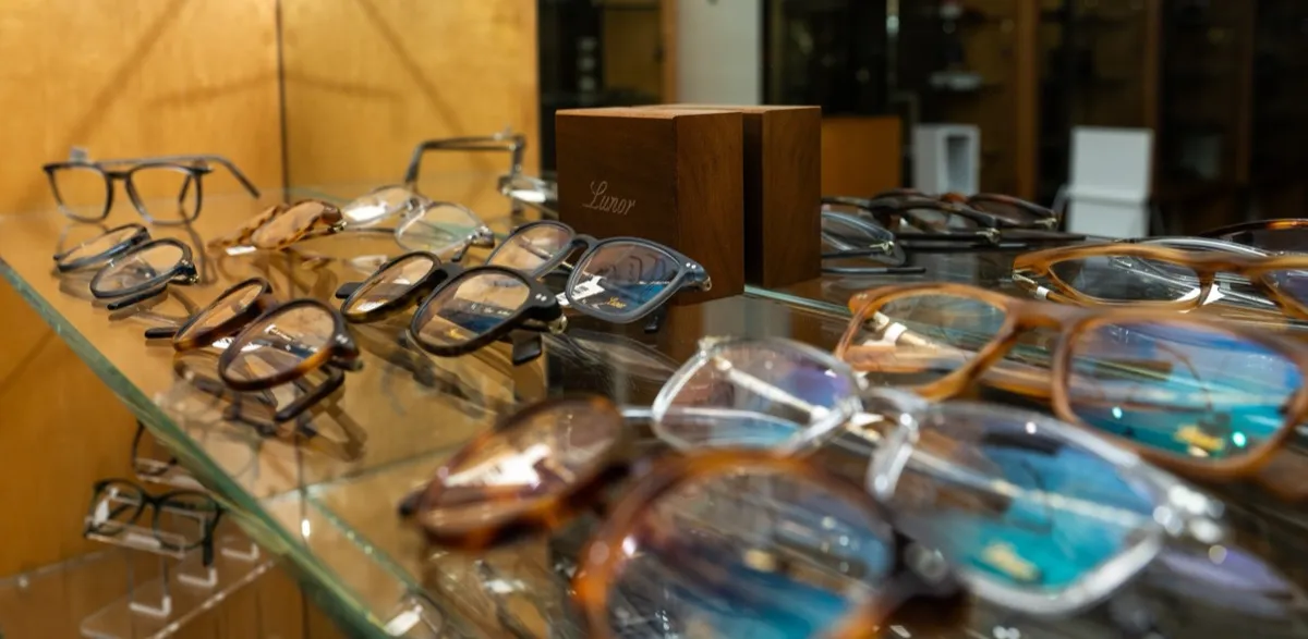 Lunor frames on a glass shelf beside a Lunor-branded wood display block at Voorthuis