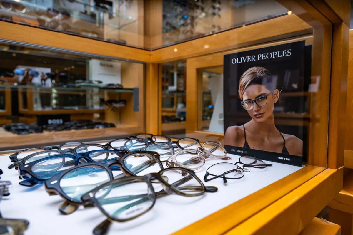 Oliver Peoples frames on a lit display shelf beside the Los Angeles lookbook at Voorthuis