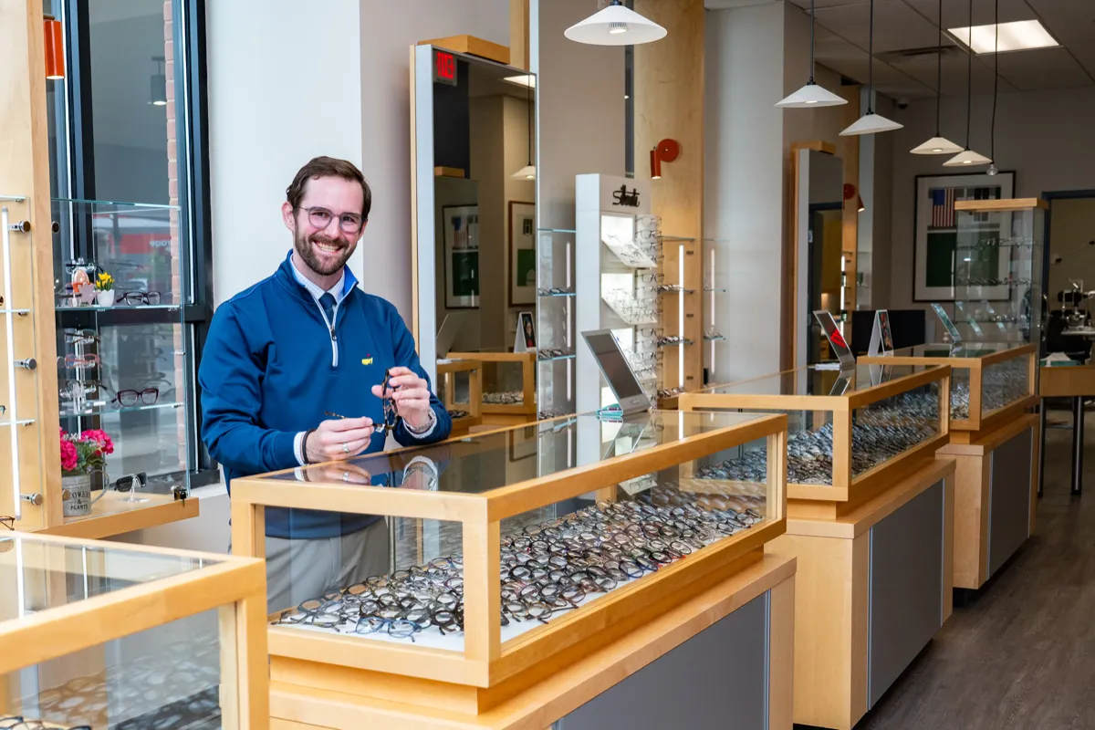 A Voorthuis optician holding a pair of glasses beside the frame display counters