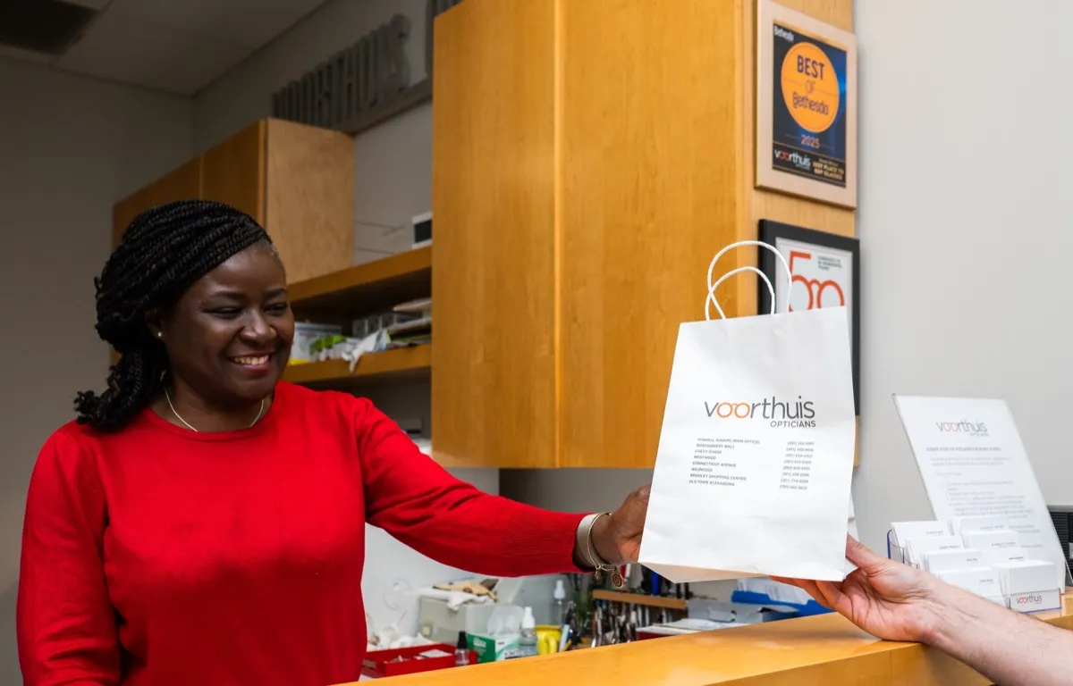 A Voorthuis staff member handing a branded bag to a customer at the front desk