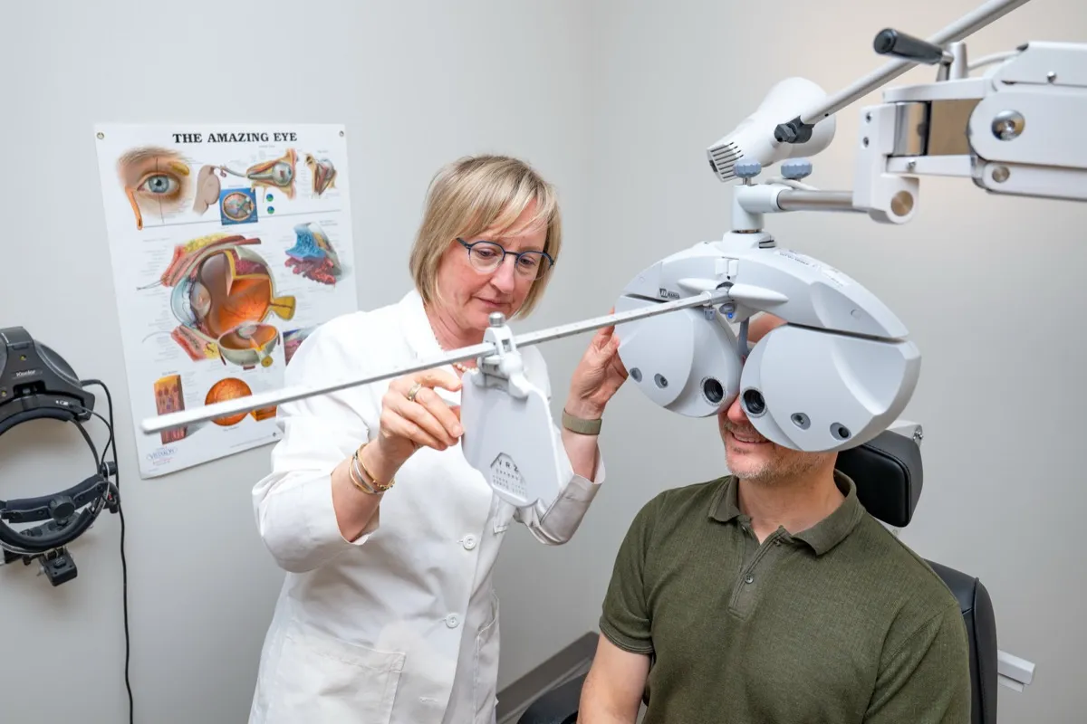 A Voorthuis optometrist measuring a patient's prescription with a digital phoropter during a comprehensive eye exam.