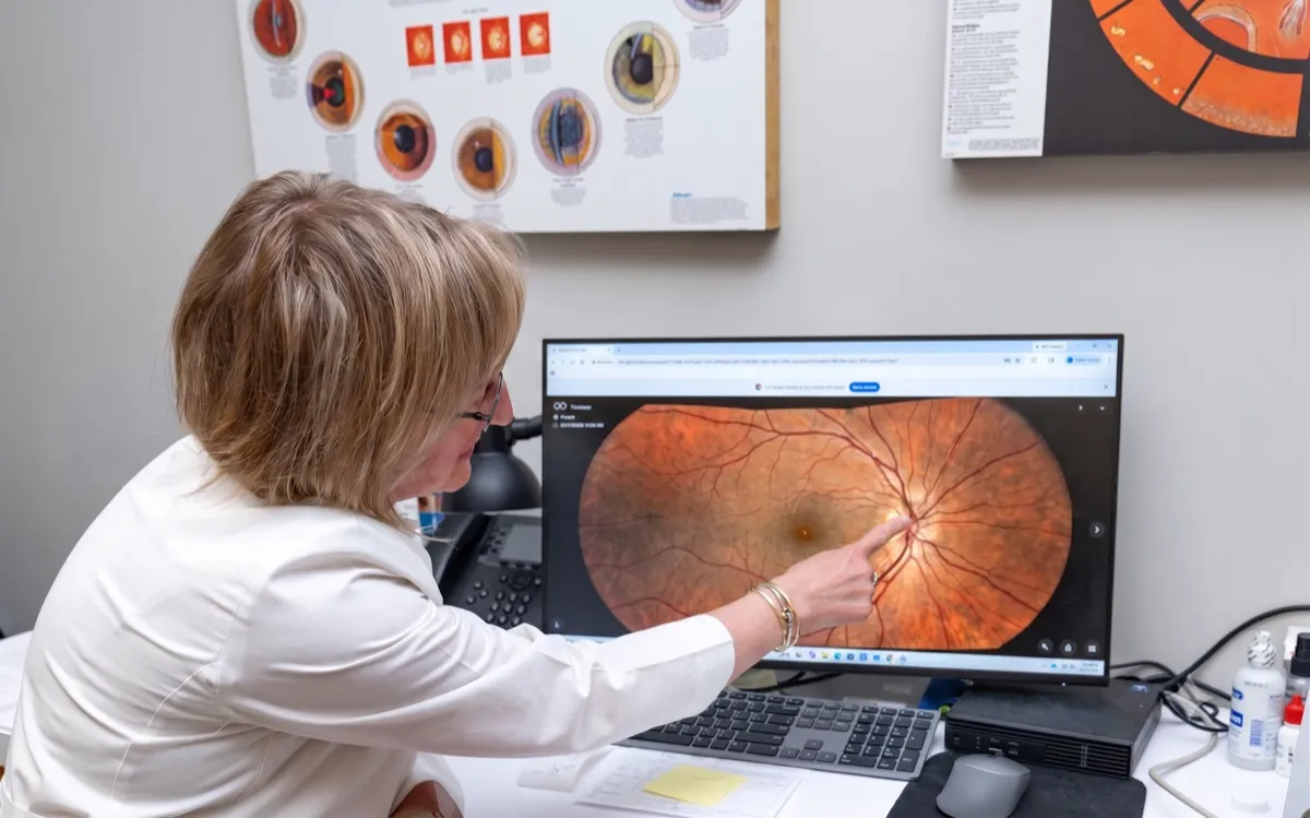A Voorthuis optometrist reviewing a patient's retinal image on a monitor during an eye exam