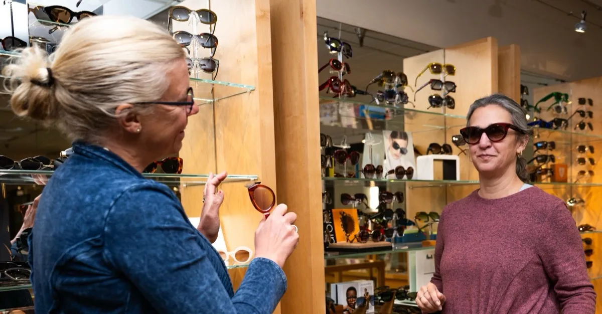 A Voorthuis optician helping a customer choose sunglasses by the display wall